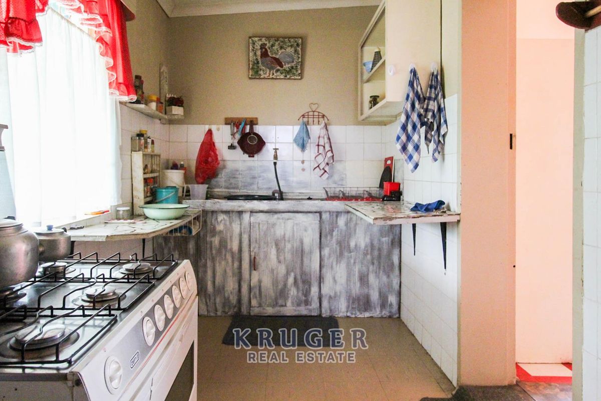 A dated kitchen featuring a gas stove, tiled splashback, and built-in cabinetry, offering potential for a modern renovation.
