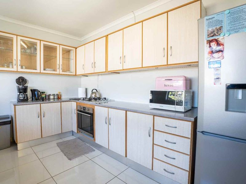 A functional kitchen featuring light-toned laminate cabinetry, built-in oven, gas hob, and tiled flooring, offering a clean and practical workspace.