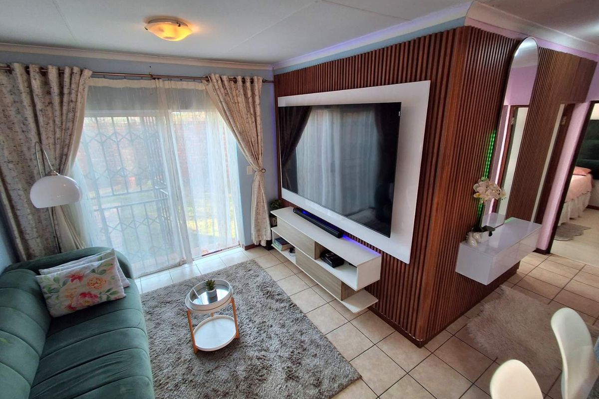A modern living room featuring a decorative timber slat feature wall, tiled flooring, and sliding glass doors leading to an outdoor area.