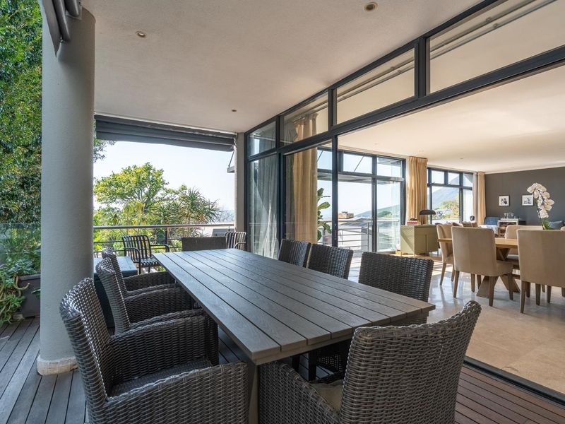 Spacious covered balcony featuring timber decking, glass balustrades, and large sliding doors providing seamless indoor-outdoor flow to the living area.