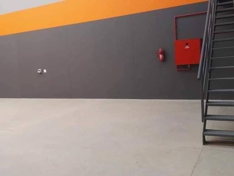 Spacious industrial utility area featuring concrete flooring, a metal staircase, and wall-mounted fire safety equipment.