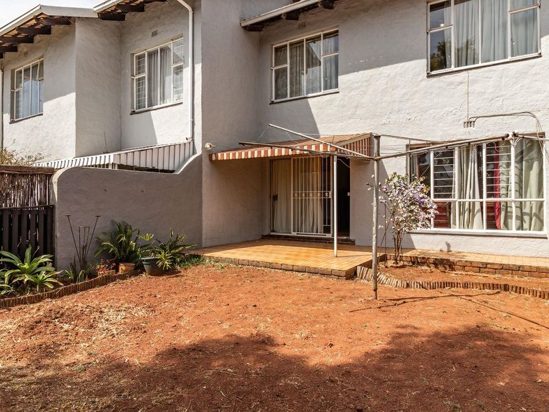 Rear view of the townhouse featuring a tiled patio, sliding door access, and a private garden area with a metal washing line.