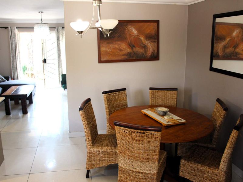 A dining area featuring tiled flooring and a central light fixture, with an open-plan layout leading to the adjacent living space.