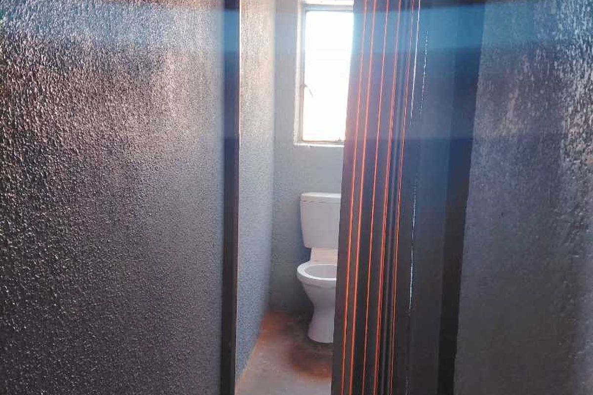 A small, basic bathroom featuring a toilet and a folding door, requiring cosmetic updates to improve the overall finish and appeal.