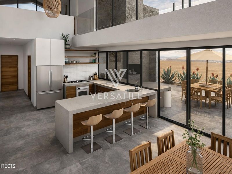 Modern open-plan kitchen featuring a central island, sleek cabinetry, and expansive glass sliding doors opening to an outdoor patio area.