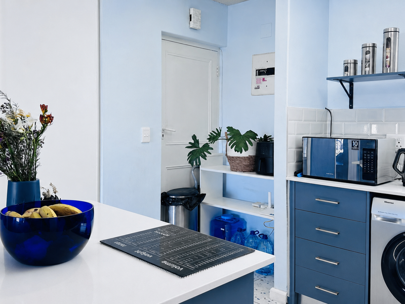 A functional kitchen area featuring blue cabinetry, subway tile backsplash, and an integrated washing machine with a clean, modern aesthetic.