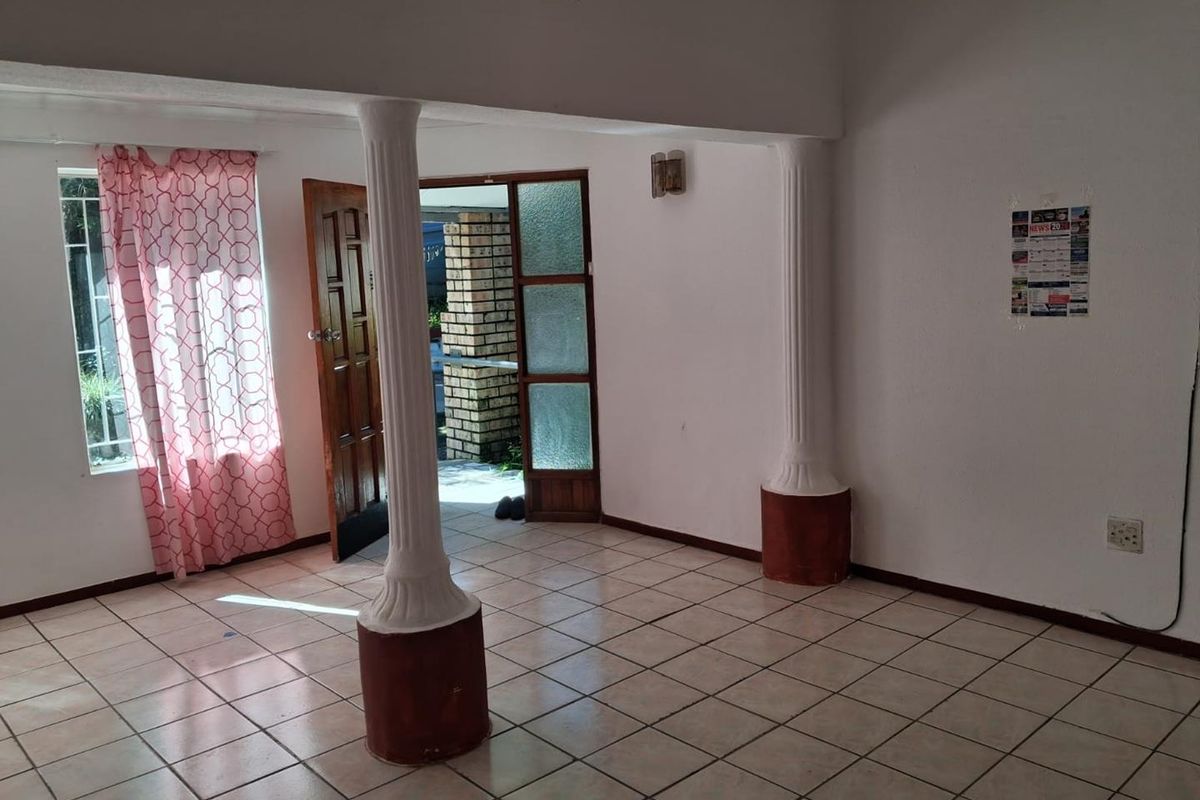 An open-plan living area featuring ceramic tiled flooring, decorative columns, and direct access to an outdoor patio area.