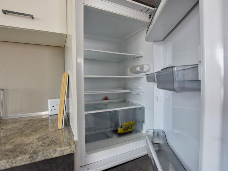 A close-up view of an integrated refrigerator unit set within kitchen cabinetry featuring a granite countertop.