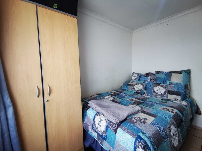 A compact bedroom featuring tiled flooring and neutral wall finishes, providing a functional space for rest.
