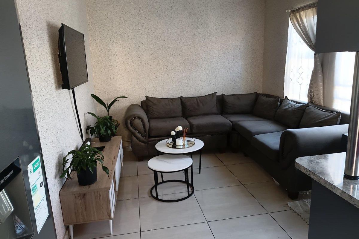 A compact living room featuring neutral tiled flooring and coved ceiling cornices, providing a functional and well-maintained space.