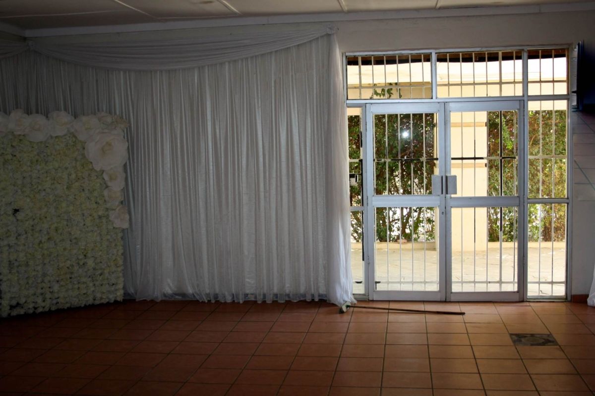 Interior view of a room featuring tiled flooring and a large glass door with security bars leading to an outdoor area.