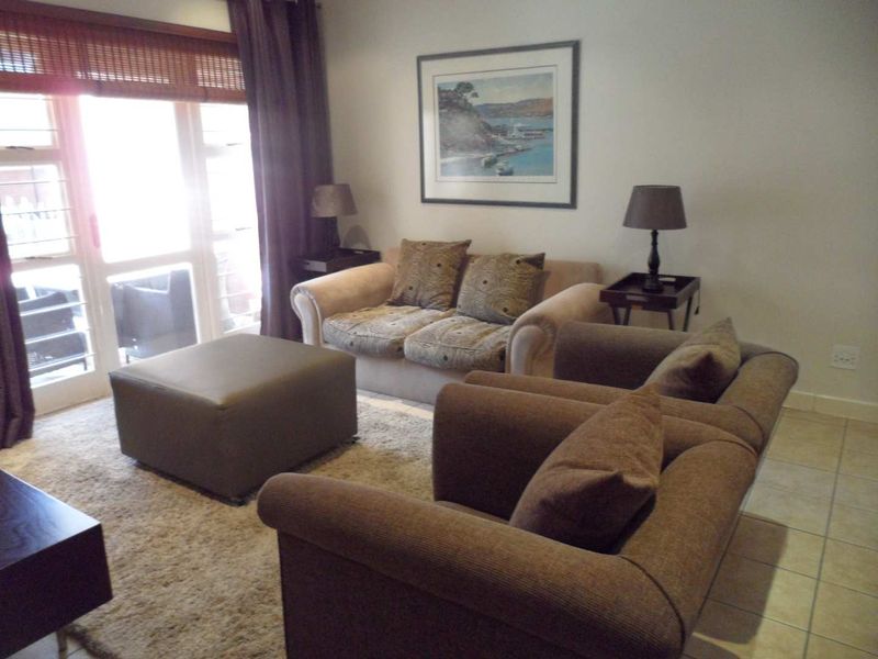 A comfortable living room featuring tiled flooring and a large sliding glass door that provides access to the outdoor area.