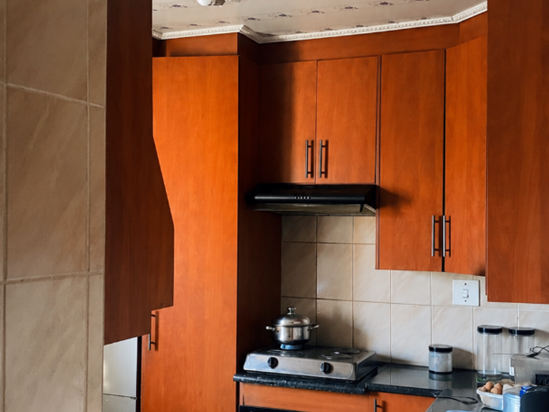 A functional kitchen featuring warm-toned wooden cabinetry, granite countertops, a built-in oven with gas hob, and a tiled backsplash.