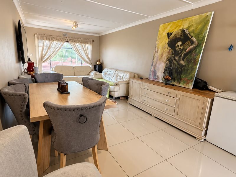 Open-plan living and dining area featuring neutral tiled flooring and coved ceilings, offering a versatile space for relaxation and entertaining.