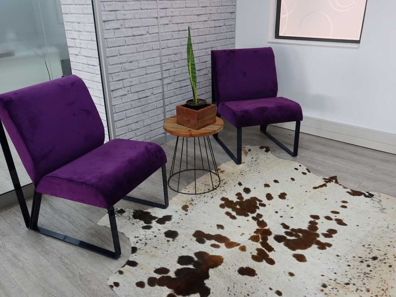 A modern office waiting area featuring a textured brick accent wall, light wood-look laminate flooring, and a contemporary glass partition.