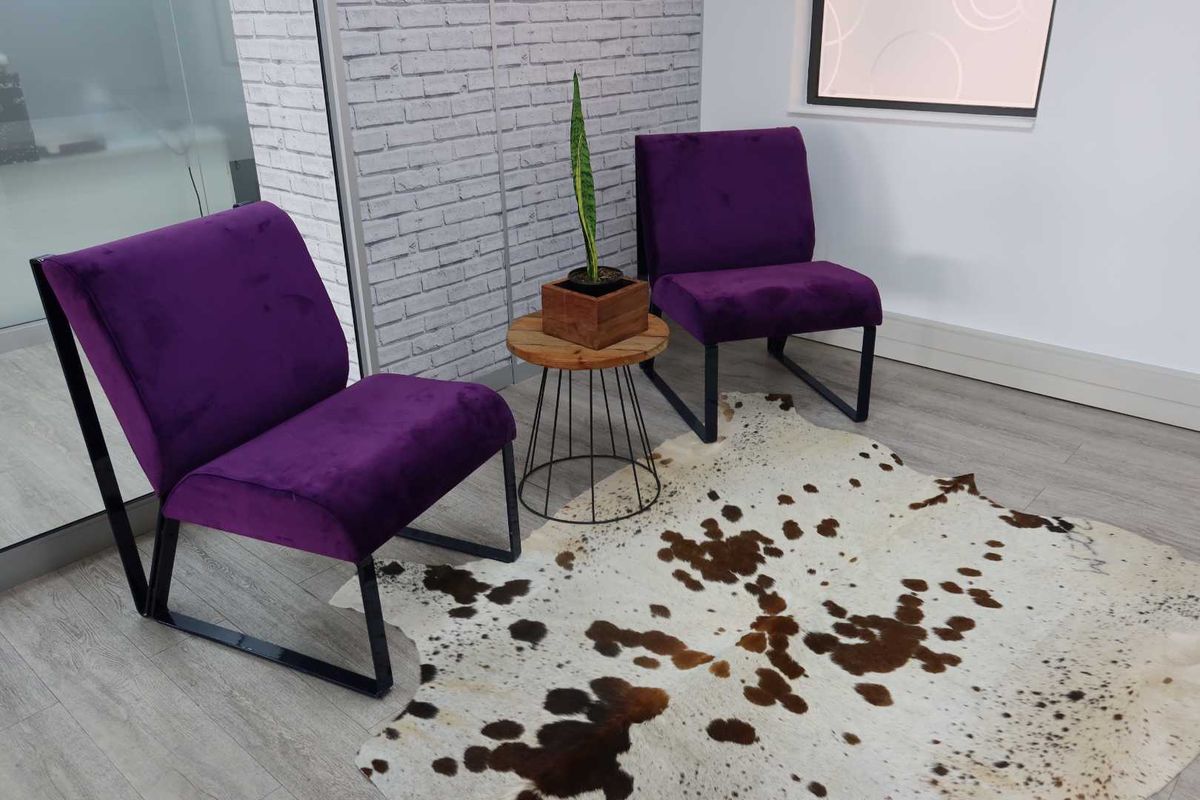 A modern office waiting area featuring a textured brick accent wall, light wood-look laminate flooring, and a contemporary glass partition.