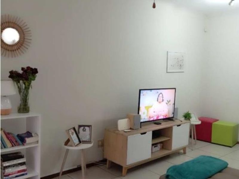 A living room area featuring neutral tiled flooring and plain white walls, providing a functional and versatile space for relaxation.