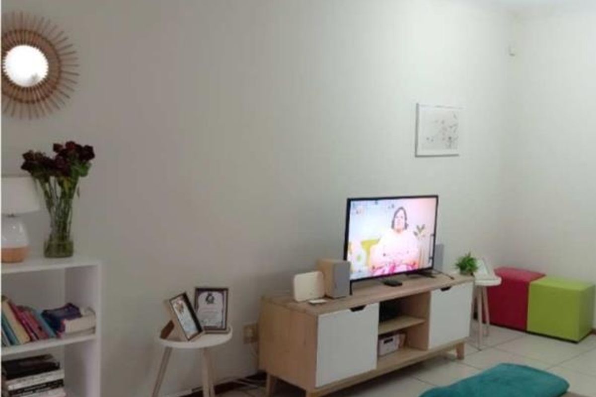A living room area featuring neutral tiled flooring and plain white walls, providing a functional and versatile space for relaxation.