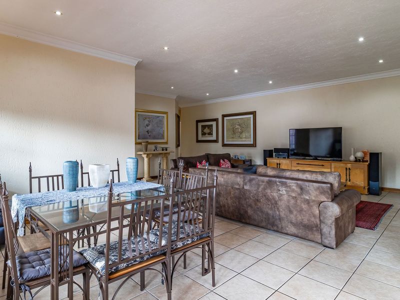 Spacious open-plan living and dining area featuring neutral walls, ceramic tiled flooring, and recessed downlighting throughout.