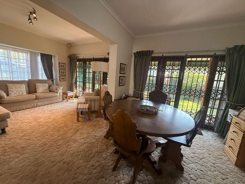 Spacious open-plan living and dining area featuring large sliding glass doors with security gates, providing direct access to the garden.