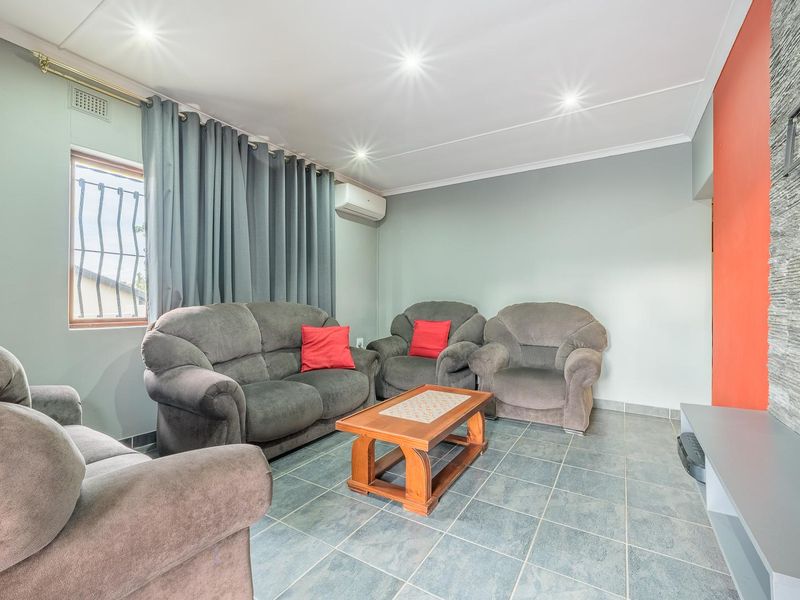 A comfortable living room featuring tiled flooring, a stone-cladding feature wall, and a split-system air conditioner for climate control.