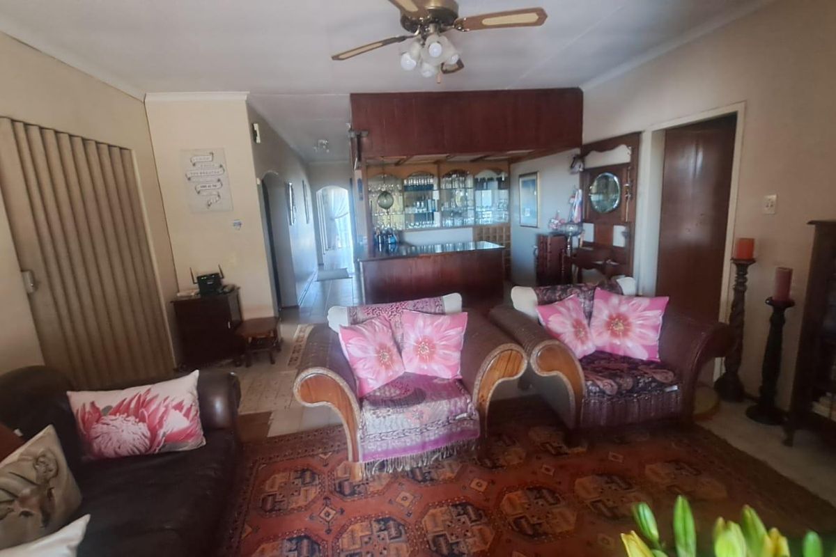 A living room featuring a built-in wooden bar area, ceiling fan, and tiled flooring, providing a functional space for entertaining.