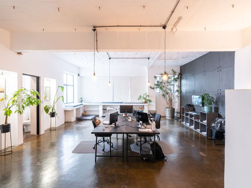 Spacious open-plan office featuring polished concrete floors, exposed industrial ceiling details, and a modern feature wall, offering a bright and contemporary workspace.