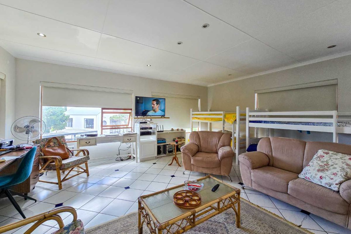 Spacious living area featuring tiled flooring, recessed ceiling lighting, and large windows with roller blinds.