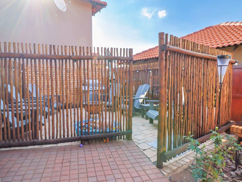 A private outdoor patio area featuring timber pole fencing and paved flooring, providing a secluded space for outdoor relaxation.