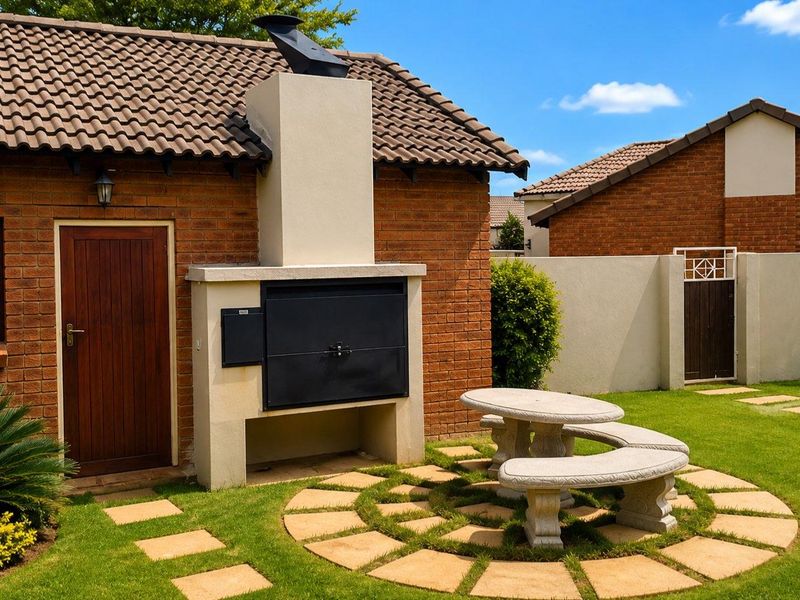 A well-maintained outdoor patio area featuring a built-in braai, brick exterior, and paved seating area set within a private garden.