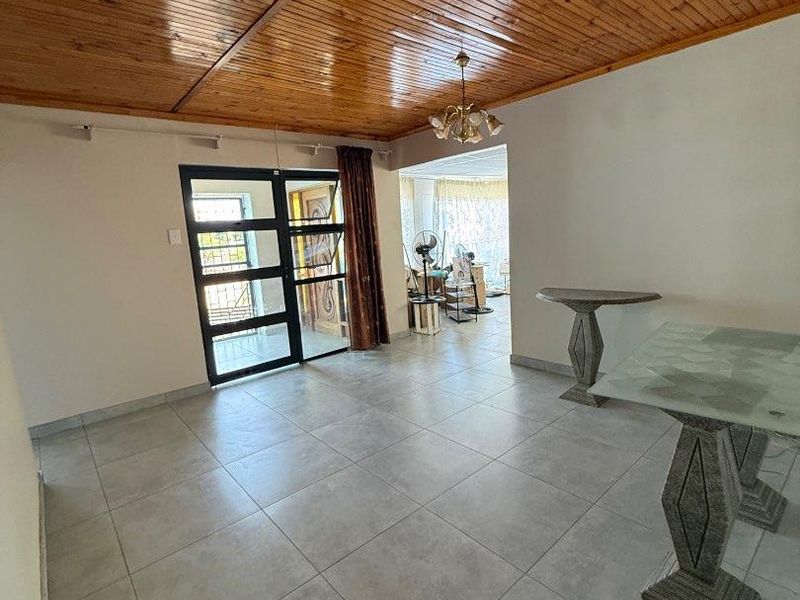 Spacious living area featuring large format floor tiles and a warm timber tongue and groove ceiling with direct access to the entrance.