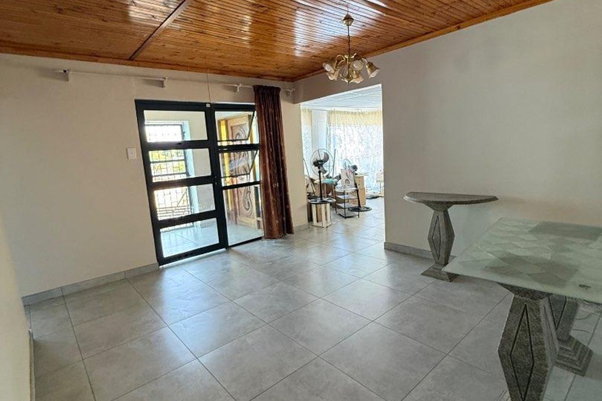 Spacious living area featuring large format floor tiles and a warm timber tongue and groove ceiling with direct access to the entrance.