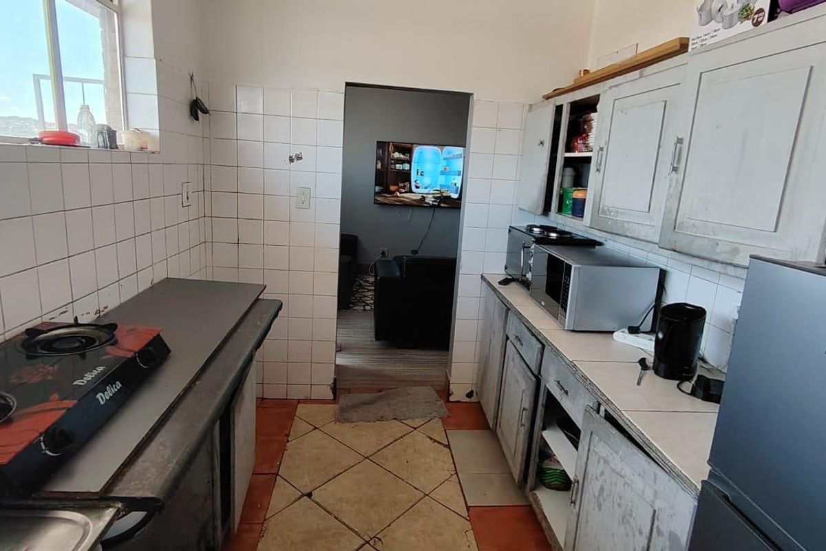 A functional kitchen featuring built-in cabinetry, tiled walls, and a gas hob, providing a practical workspace with direct access to the adjacent living area.