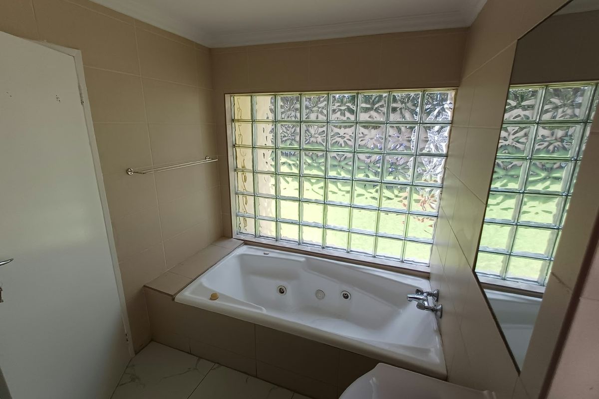 A bathroom featuring a built-in bathtub, tiled finishes, and a distinctive glass block window providing natural light.