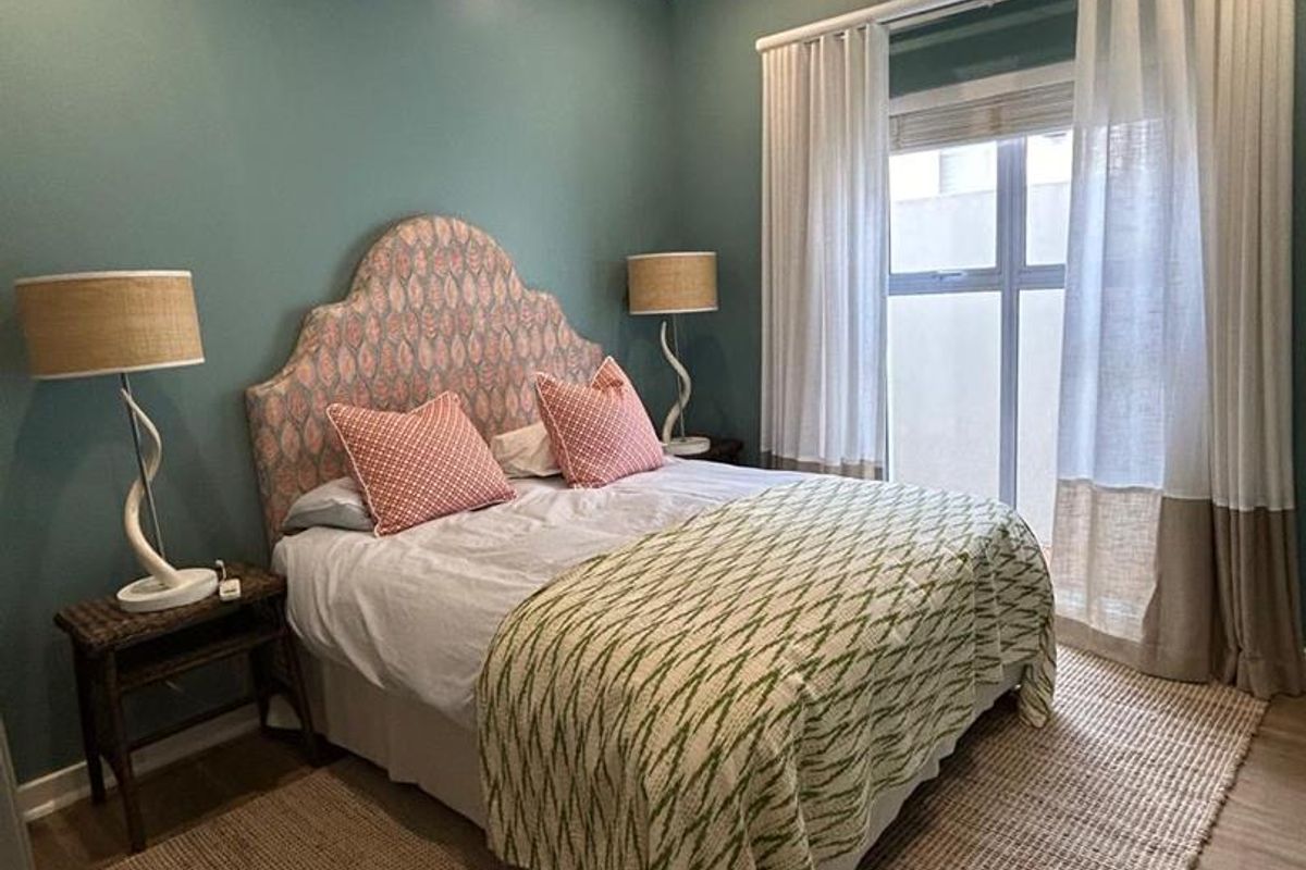 A well-maintained bedroom featuring laminate flooring, recessed downlighting, and a wall-mounted split-system air conditioning unit.