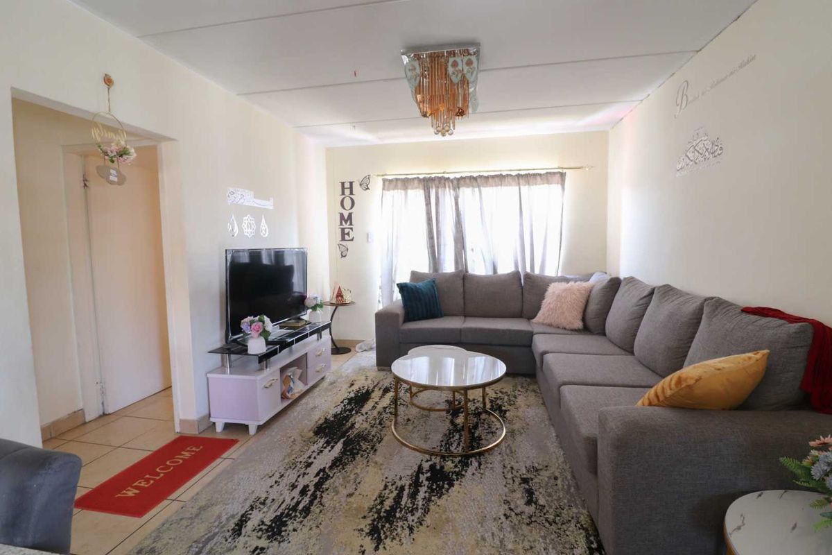 A comfortable living room featuring tiled flooring and a central ceiling light fixture, providing a functional and inviting space for relaxation.