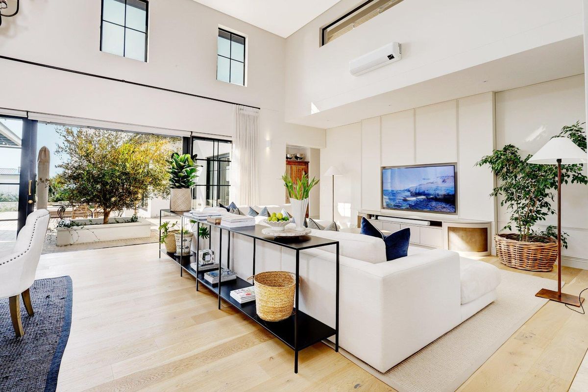 Spacious living room featuring high ceilings, large windows, integrated cabinetry, and seamless flow to an outdoor patio area.