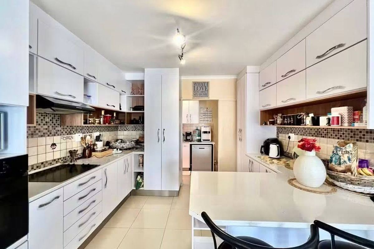 Modern kitchen featuring white cabinetry, stone countertops, integrated appliances, and a tiled backsplash, offering a clean and functional workspace.