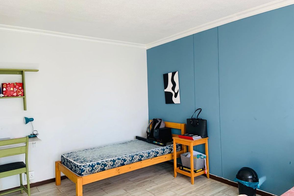 A bedroom featuring tiled flooring, a blue accent wall, and white walls with crown molding.