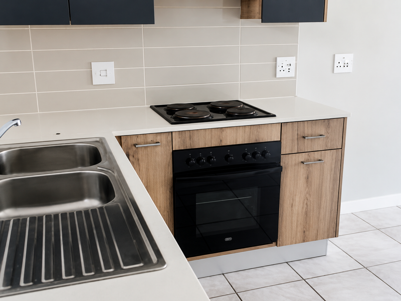 Modern kitchen featuring wood-finish cabinetry, stone countertops, a built-in oven with electric hob, and a double stainless steel sink with tiled splashback.