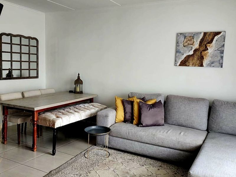 An open-plan living and dining area featuring neutral tiled flooring and a clean, minimalist aesthetic suitable for various interior design styles.