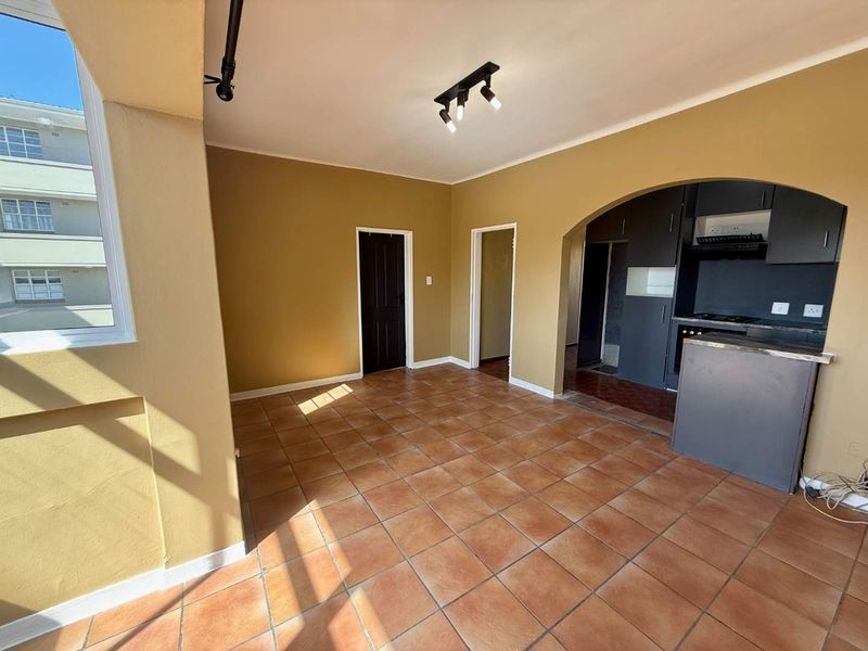 Open plan living area featuring ceramic tile flooring, an arched transition to the kitchen, and built-in cabinetry with integrated appliances.