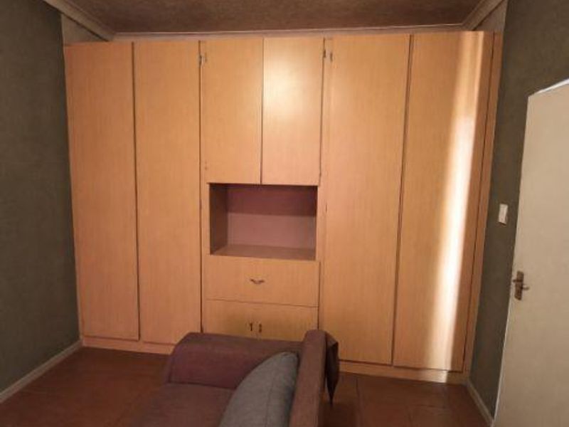 Bedroom featuring floor-to-ceiling built-in wooden cupboards and tiled flooring.