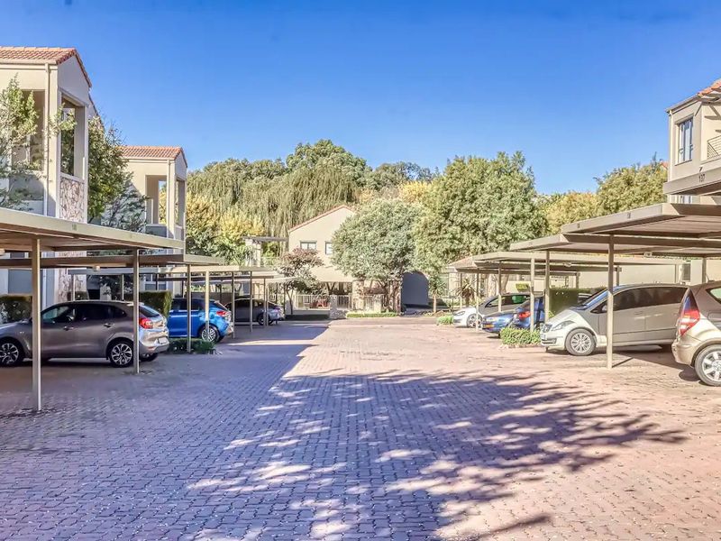 Exterior view of the apartment complex featuring a paved driveway and covered carport parking bays for residents.