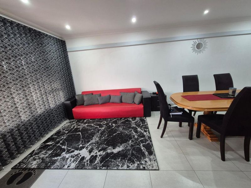 Open plan living and dining area featuring neutral tiled flooring and recessed ceiling lighting.