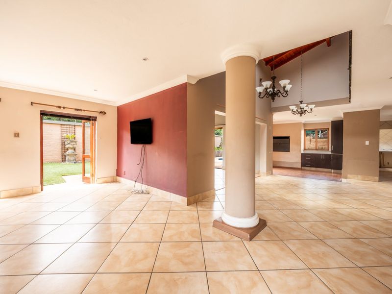Spacious open-plan living area featuring ceramic floor tiles, a structural column, and direct access to the garden through double doors.