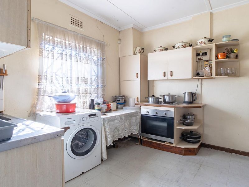 A dated kitchen featuring built-in cabinetry, an integrated oven, and tiled flooring, requiring cosmetic updates to modernize the space.