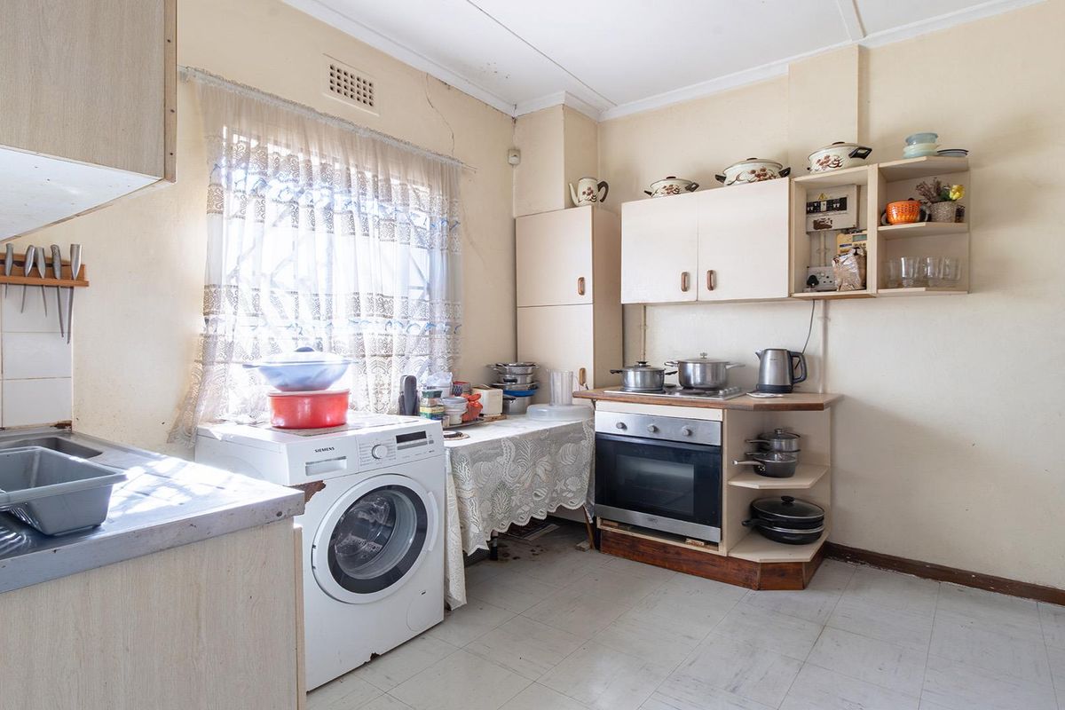 A dated kitchen featuring built-in cabinetry, an integrated oven, and tiled flooring, requiring cosmetic updates to modernize the space.