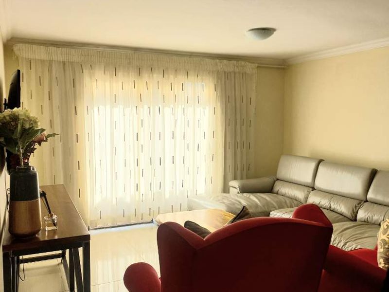 A bright living room featuring tiled flooring, a recessed ceiling light, and a large sliding glass door providing natural light.