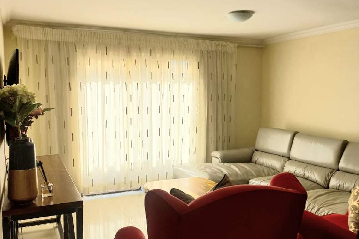 A bright living room featuring tiled flooring, a recessed ceiling light, and a large sliding glass door providing natural light.